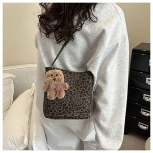 Dettaglio borsa a tracolla leopardata con cinturino verde e ciondolo orsetto di peluche