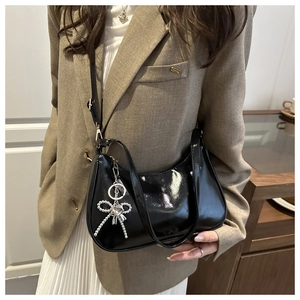 Detail van zwarte lakschouder tas met een zilveren strass strik hanger voor dames