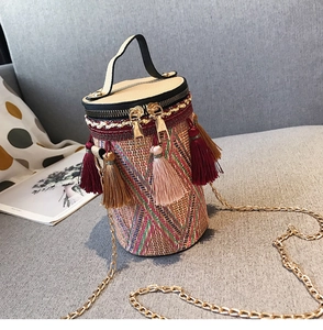 Dettaglio borsa a secchiello in paglia boho con motivi colorati e nappe vivaci applicate