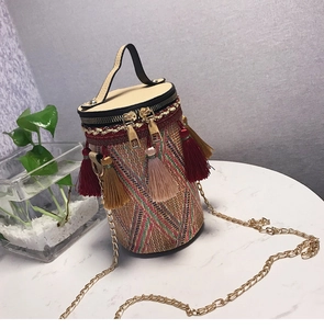 Dettaglio borsa a secchiello in paglia boho con nappe colorate e catena d'oro