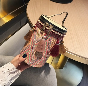 Dettaglio borsa a secchiello etnica intrecciata con nappe colorate e manico in pelle