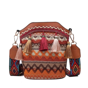 Borsa a secchiello in paglia stile etnico con nappine colorate e tracolla larga tessuta