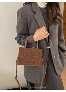 Detail view of stylish leopard print handbag with leather handle and shoulder strap