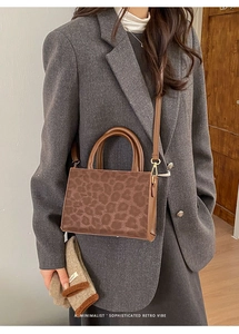 Close-up of retro leopard print tote bag with brown leather handles and gold hardware