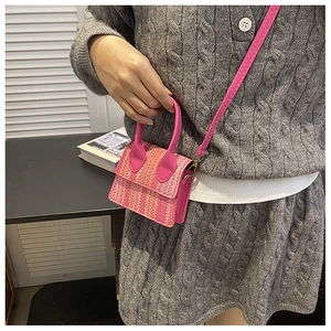 Detail of pink woven texture crossbody bag with handle and gold metal hardware