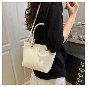 Detail view of white leather tote bag featuring unique knot handle and adjustable strap