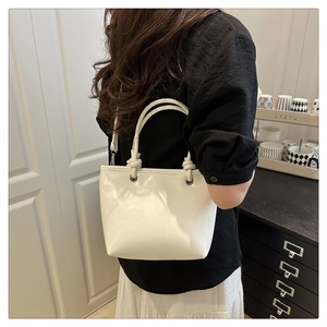 Détail d'un sac seau en cuir verni blanc brillant avec poignées nouées élégantes