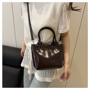 Détail du sac cabas marron foncé brillant montrant les ferrures argentées et le similicuir