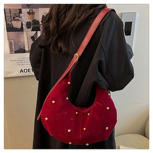 Dettaglio della borsa hobo in velluto bordeaux con borchie dorate e tracolla sottile