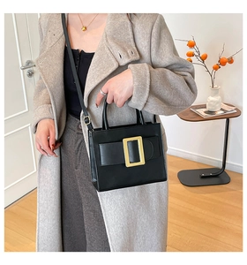 Close-up of minimalist black square bag with iconic gold buckle on an elegant model
