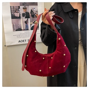 Dettaglio borsa a mezzaluna bordeaux con borchie dorate e texture in velluto opaco