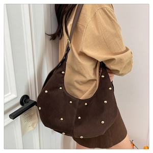 Dettaglio della borsa hobo a mezzaluna in camoscio marrone scuro con borchie dorate e tracolla