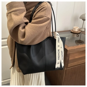 Dettaglio di una grande borsa tote nera con un foulard decorativo in seta sul manico