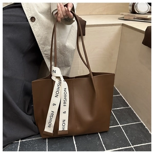 Dettaglio della borsa tote marrone in ecopelle con nastro fashion e finitura ruvida