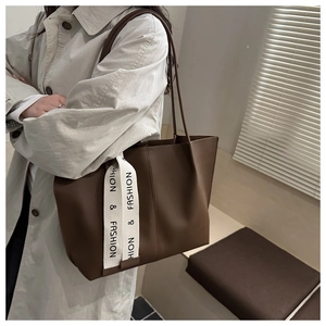 Dettaglio della borsa tote in pelle marrone scuro con nastro in tela bianca e logo testo