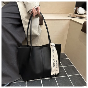 Dettaglio della borsa tote in pelle nera con cuciture verticali e cinturino fashion