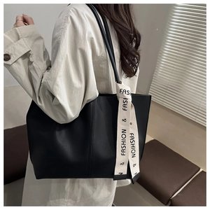 Dettaglio della borsa tote grande in pelle nera con nastro moda bianco e cuciture a vista