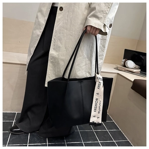 Dettaglio di una grande borsa tote nera con texture opaca e foulard in seta stampato