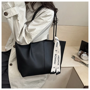 Dettaglio della borsa tote in pelle nera con foulard decorativo in un contesto lifestyle