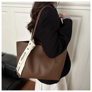 Dettaglio di una grande borsa tote marrone con nastro decorativo su modella