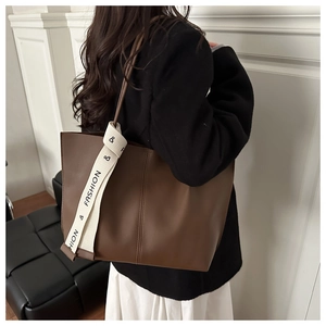 Dettaglio di una grande borsa tote marrone con cinturino FASHION indossata da modella