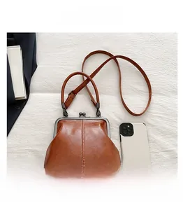 Detailed macro view of vintage brown leather shell bag with metal clasp and phone for scale