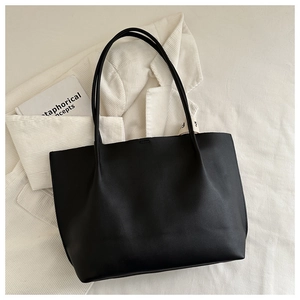 Dettaglio di una borsa tote in pelle nera abbinata a una camicia bianca minimalista