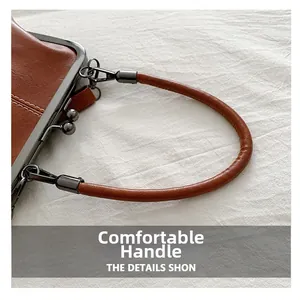 Close-up of brown vintage leather handle with dark metal hardware on textured shell bag