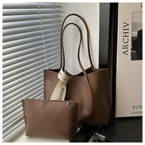 Dettaglio borsa tote in pelle marrone con pochette coordinata e nastro intrecciato