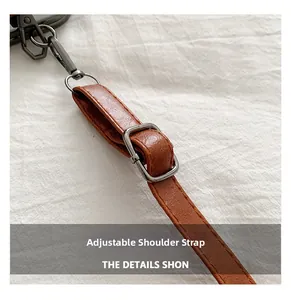 Detailed close-up of a brown leather adjustable shoulder strap with gunmetal hardware hooks