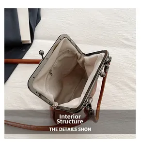 Detail view of the vintage kiss-lock bag showing herringbone lining and inner zipper pocket