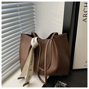 Dettaglio di borsa tote marrone scuro con nastro moda sul davanzale della finestra