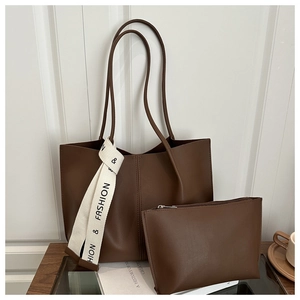 Dettaglio della borsa tote in pelle marrone con nastro moda e piccola pochette coordinata