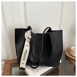 Dettaglio di una grande borsa tote nera con tracolla decorativa color crema e testo Fashion