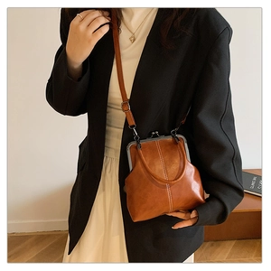 Detailed view of a vintage brown leather shell bag with metal clasp and slim strap