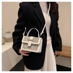 Close-up of beige monogram crossbody bag with gold metal buckle on model in black suit