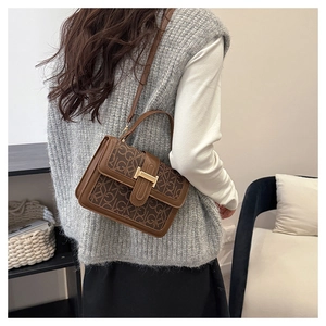 Detail showing vintage brown crossbody bag with monogram pattern and golden buckle