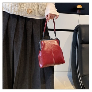 Detail of red vintage leather handbag with metal clasp and elegant white stitching