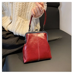 Detail of red vintage-style leather handbag with metallic clasp and white contrast stitching