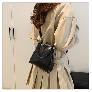 Detail of a vintage black leather crossbody bag with metallic clasp and glossy finish