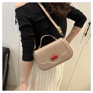 Detail of apricot shoulder bag with wavy edge design and red cherry rhinestone ornaments