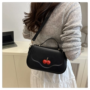 Detail shot of the red cherry buckle with sparkling crystals on the black leather bag