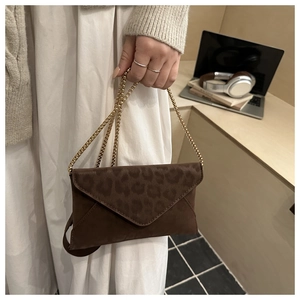 Dettaglio della pochette leopardata con catena dorata in un ambiente caldo e moderno