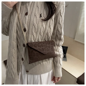 Brown leopard print envelope crossbody bag with gold chain strap on casual outfit
