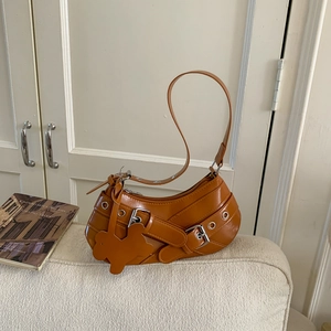 Brown faux leather underarm bag with metal buckles and cute bunny charm on sofa