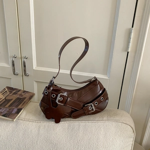 Detail view of a vintage brown PU leather shoulder bag with decorative belt straps and a bear charm
