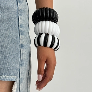 Close-up of layered chunky black and white geometric resin bracelets on a wrist
