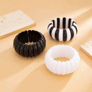 Macro view of wide elastic beaded bracelets with black and white resin finish