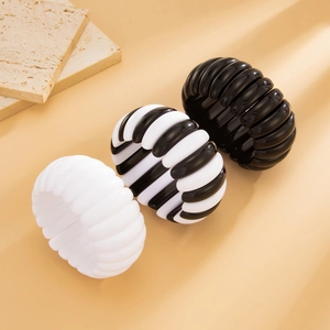 Detailed view of textured black and white irregular chunky bangles on a stone surface