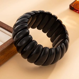 Macro shot of polished black resin stretch bracelet with smooth geometric segments